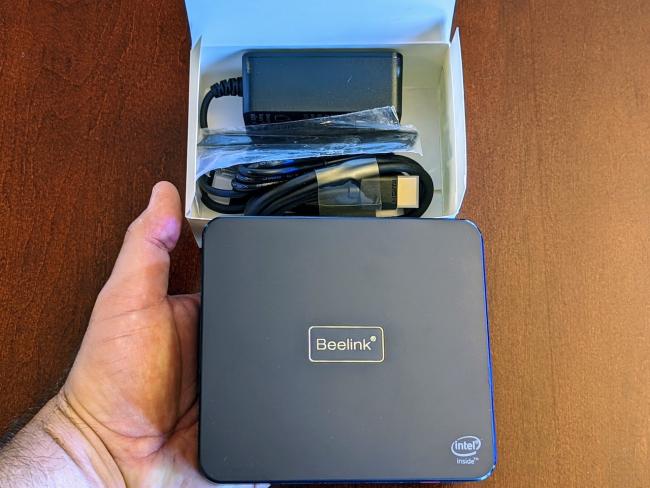 The Beelink U59 Pro in my hand along with packaging and accessories